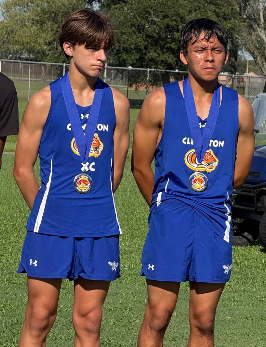 Two Clewiston High School runners in blue singlets wearing their medals