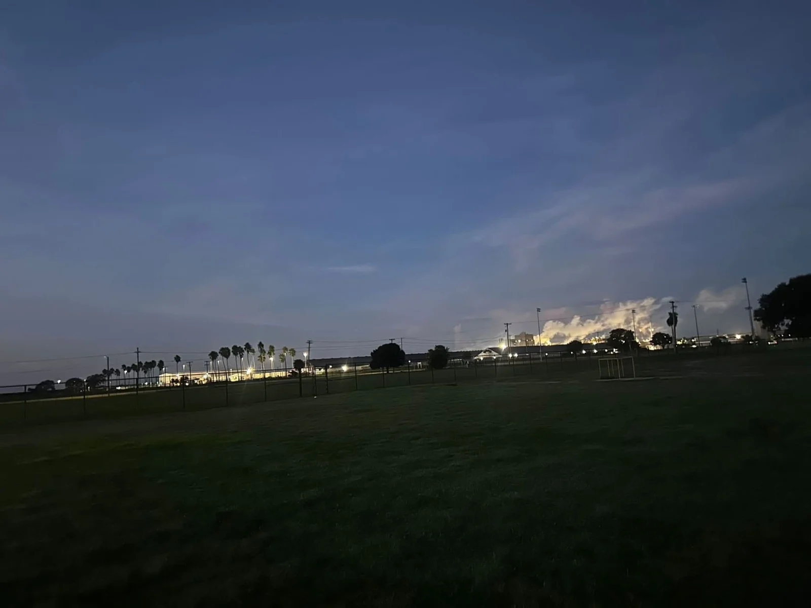 The cross country course at Clewiston High School in the half-light, with the sugar mill lit up beyond the fence
