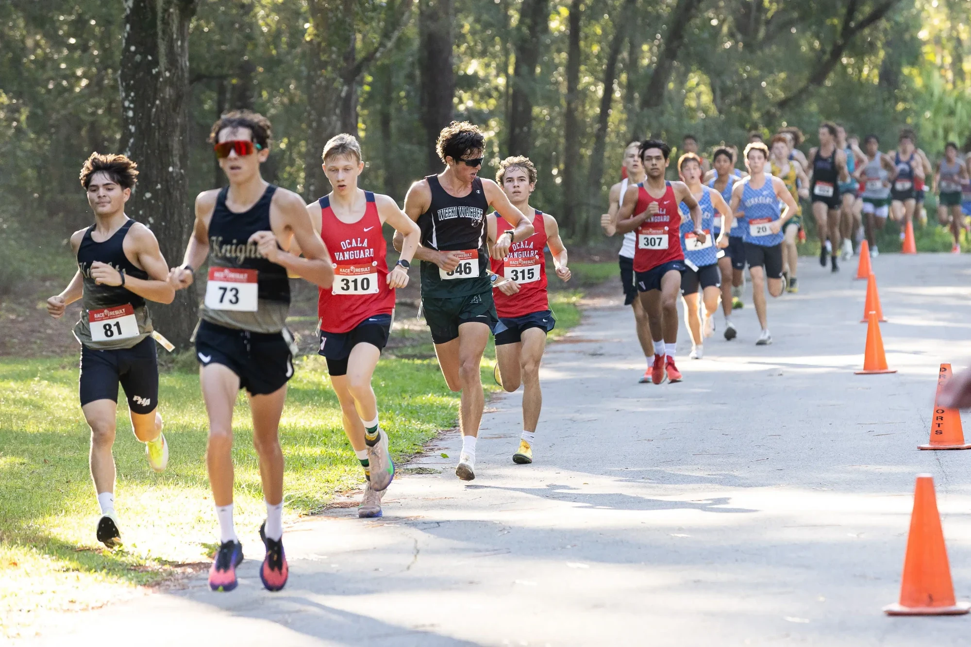 The varsity boys lead pack at the 2026 Whispering Pines Invitational, with Ocala Vanguard runners in the front group