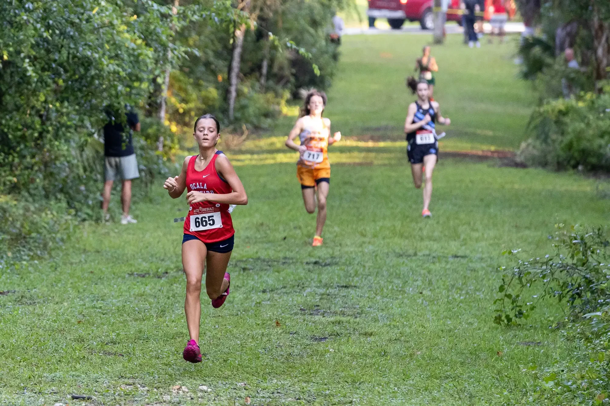 A Vanguard runner leads a chase group on the wooded course at the 2026 Whispering Pines Invitational