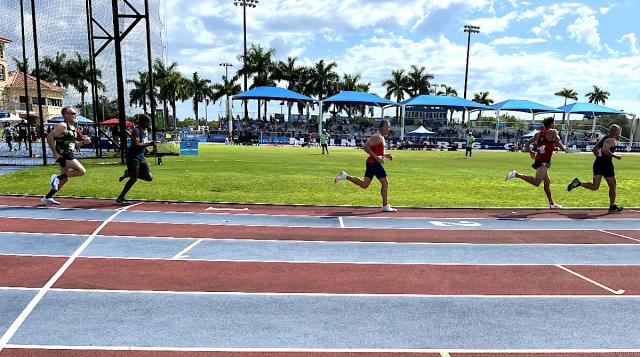 Masters runners racing the 800 meters on the Ansin Sports Complex track in Miramar, with shaded grandstands behind